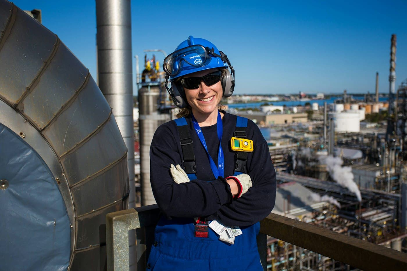 Engineer in a hard hat and coveralls smiling on an industrial plant platform