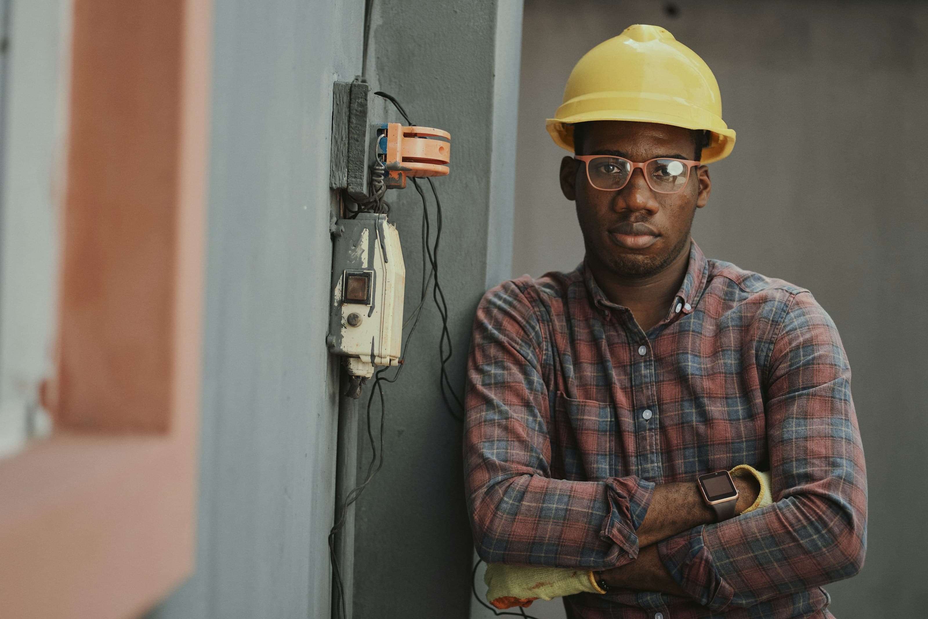 Construction worker in a yellow hard hat and safety glasses, arms crossed