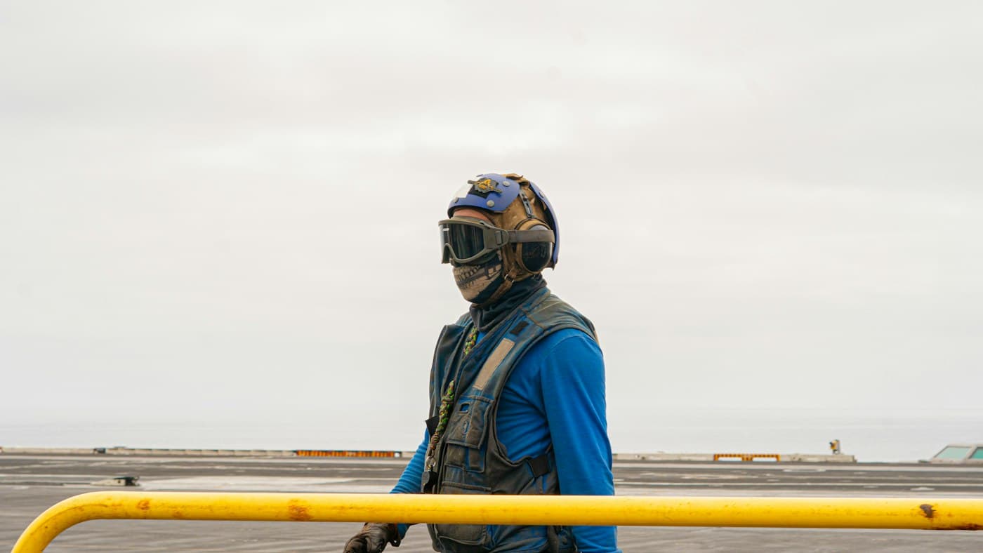 Worker in a welding mask and coveralls on the deck of a vessel at sea