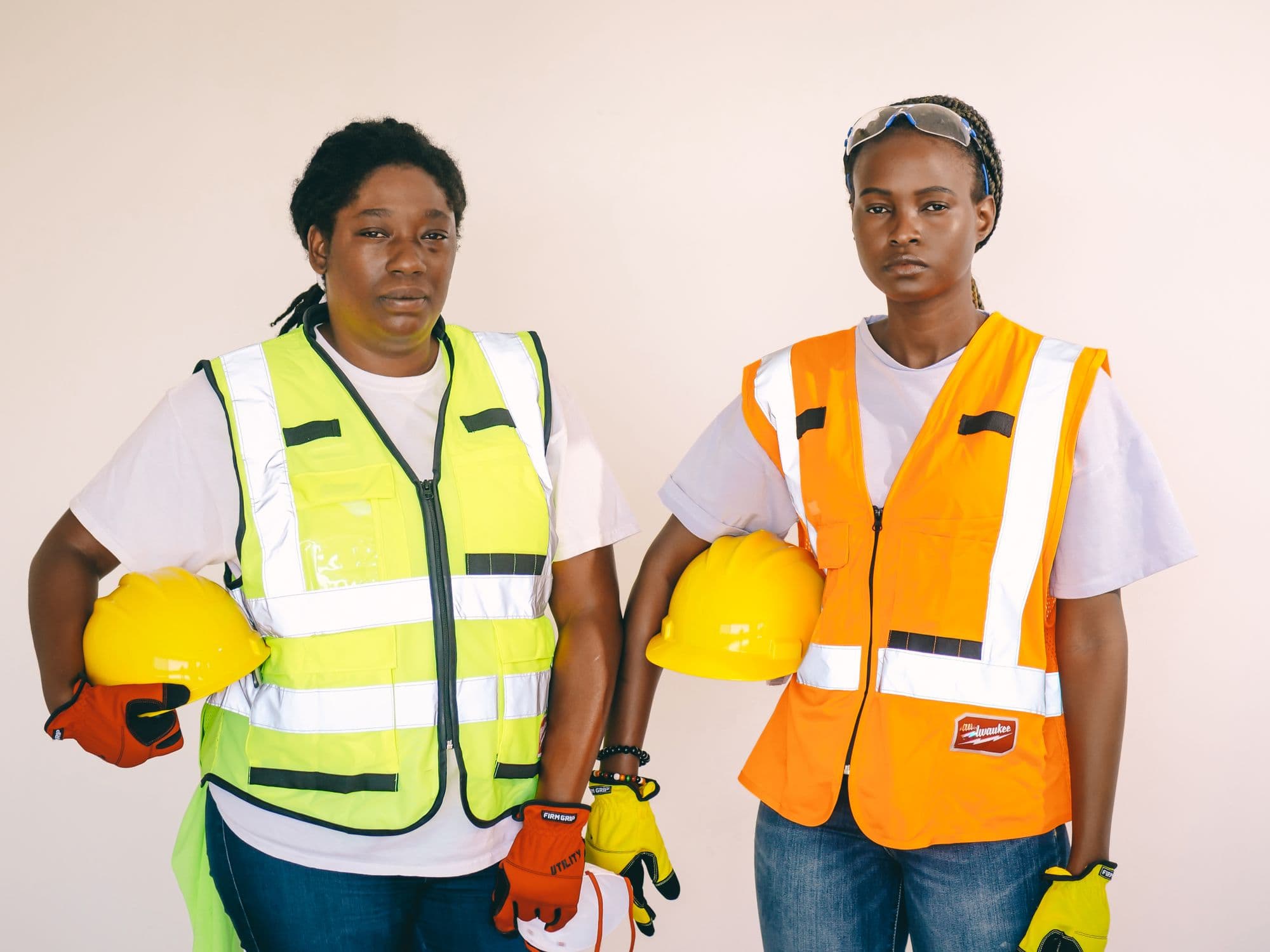 Two women in high-visibility vests holding hard hats